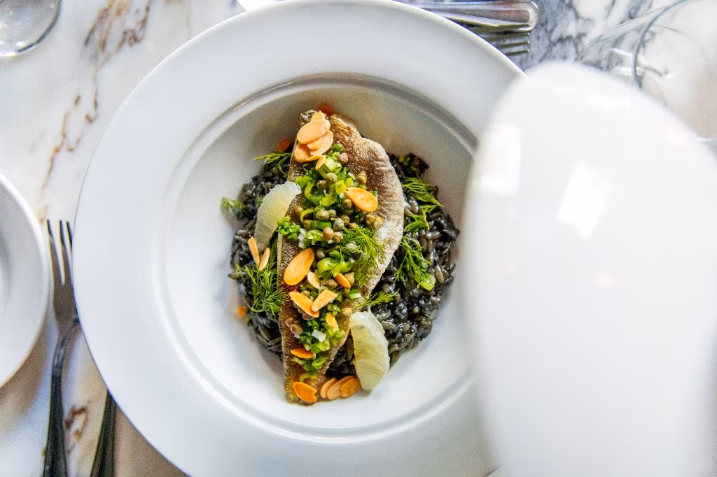 Food photography of a pan-seared fish dish on black rice