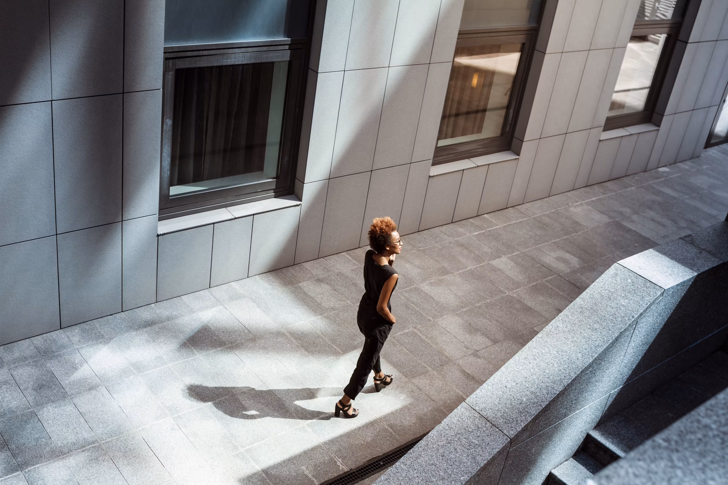 Woman walking through modern city architecture, Kairos brand tone